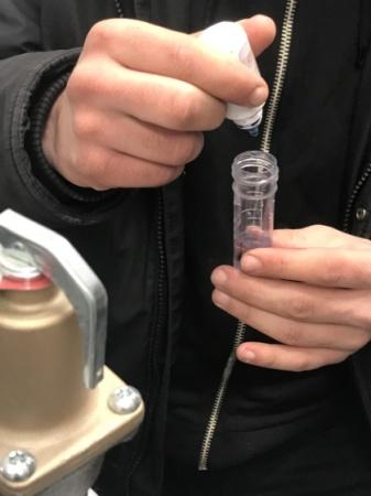 Plombier réalisant une analyse de l'eau avec un kit colorimétrique.